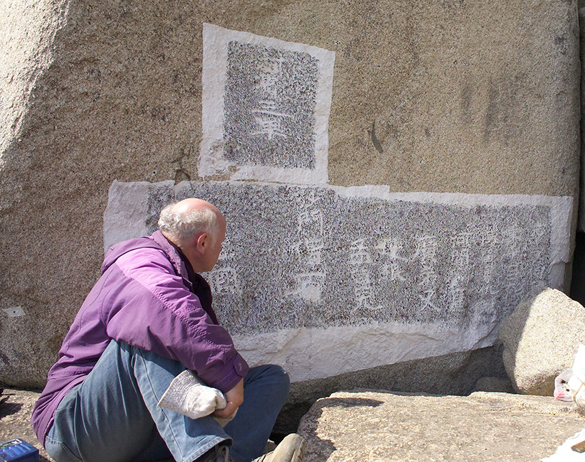 Mit Tusche betupfte Papierbahnen machen die Schriftzeichen im Fels besser sichtbar.