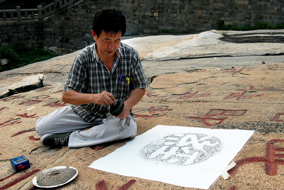 Herr Lai Fei vom Museum für die Kunst der Steinbearbeitung in Jinan stellt auf dem Diamantsutra eine Abreibung des Zeichens „Sutra" her.