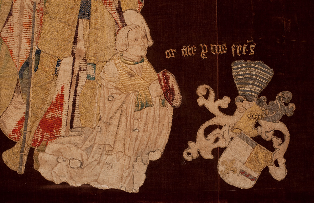 Stifterbildnis, Hochaltar-Antependium (1521), St. Viktor, Xanten. Die figürlichen Darstellungen, Wappen und Inschriften wurden auf neuen Trägerstoff appliziert und auf diese Weise bewahrt. Bei Textilien ist dies eine häufig vorkommende Form der Überlieferung.