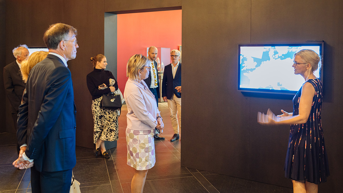 Blick in die Sonderausstellung BELLUM & ARTES im Dresdner Residenzschloss mit Besuchern vor der Medienstation zu translozierten Kunstwerken im Raum über Kunst als Beute