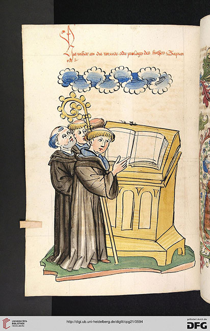 Ein Abt, gekennzeichnet durch den Krummstab, steht mit seinen Mönchen vor einem Pult, auf dem ein aufgeschlagenes Buch liegt.