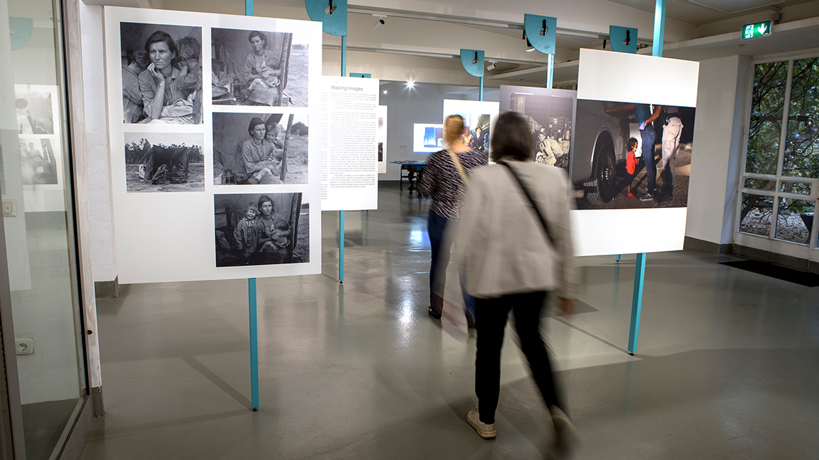 Ausstellung „Über/Sehen. Bildregime der Migration“ mit Menschen, die hindurch laufen
