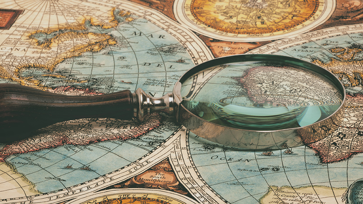 Lupe liegt auf historischem Kartenmaterial; © Adobe Stock / Andrey Burmakin 